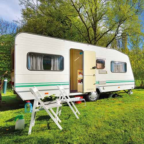 Caravan parked up on the grass with door open on a beautiful day