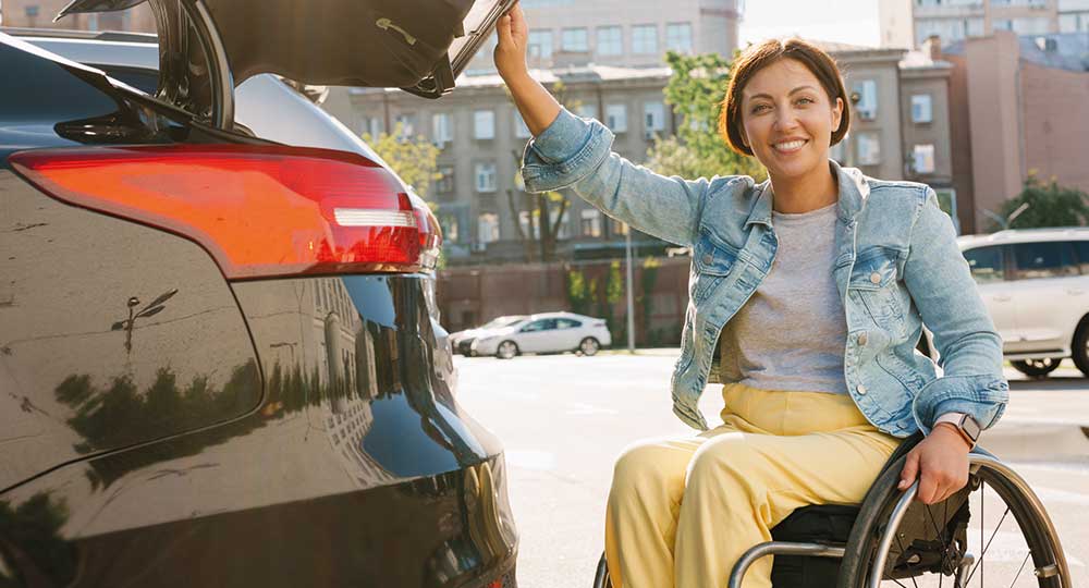 Person in wheelchair smiling into camera and holding her car boot