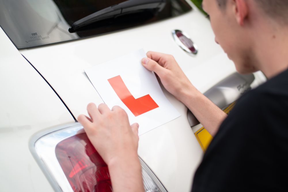 Person attaching L plates to car