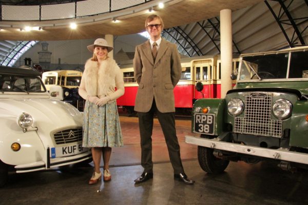 Vicki Butler-Henderson and Alex Riley in front of two cars