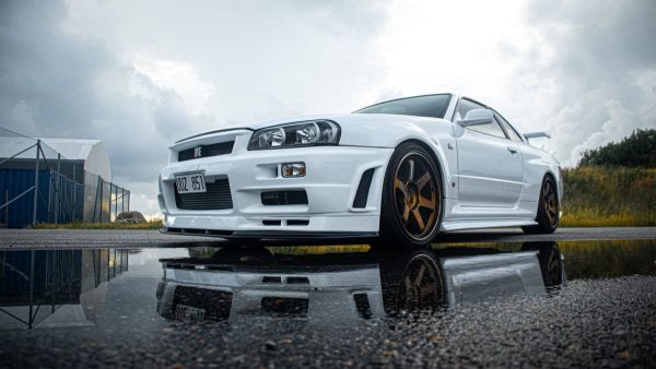 White Nissan Skyline R34 GT-R parked with moody clouds overhead