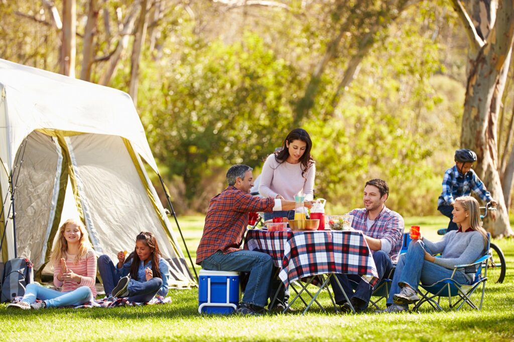 Two Families Enjoying Camping Holiday In Countryside