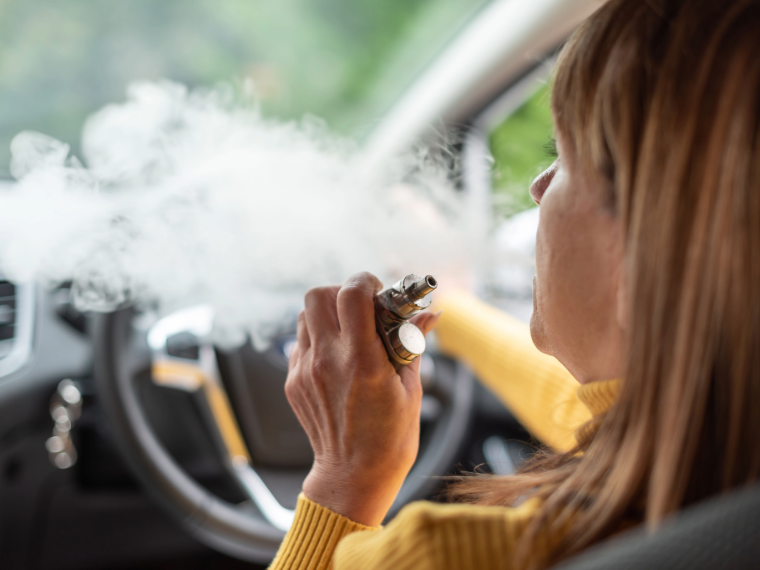Women sitting behind the wheel of a car and vaping while driving