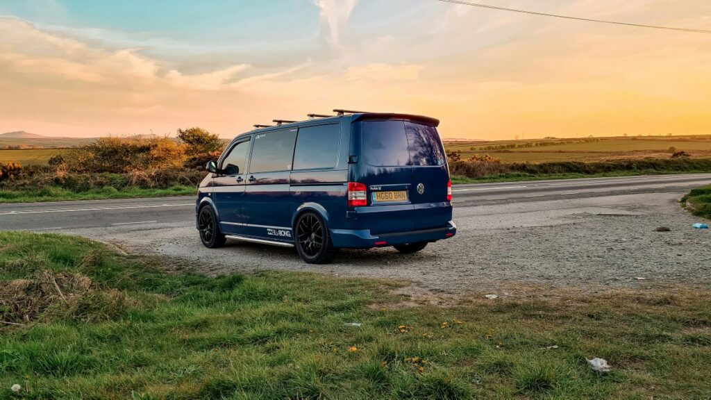 Converted blue van parked in front of a beautiful view during the sunset