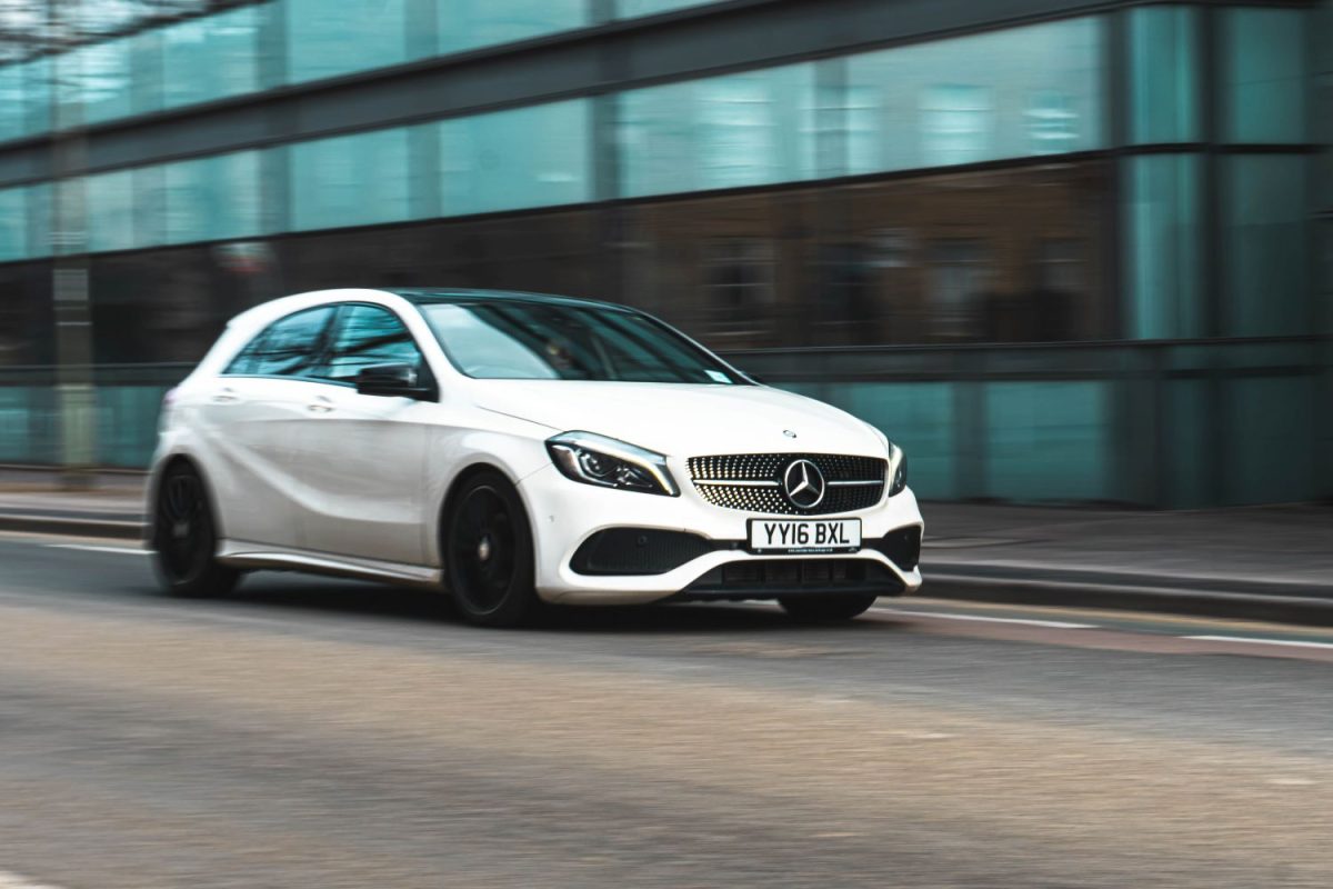White car driving down a built-up street in the UK