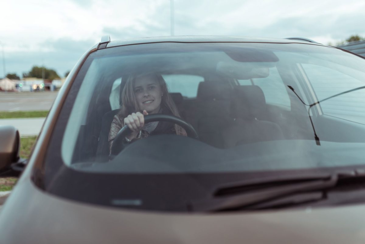 Woman sitting behind the wheel of a car smiling