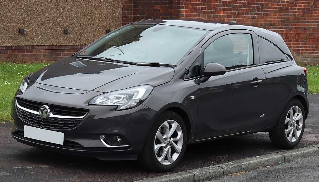 Black Vauxhall Corsa parked on a curb in front of a building